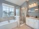 Bright bathroom featuring a shower, tub, and vanity with window view, and neutral tile at 8367 Devinney St, Arvada, CO 80005