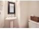 Bathroom featuring a pedestal sink, decorative mirror, and toilet with a wicker basket for added storage at 8367 Devinney St, Arvada, CO 80005