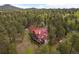 Aerial view showcasing the expansive property surrounded by a lush forest landscape and a red roof at 23076 Oehlmann Park Rd, Conifer, CO 80433