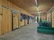 Interior barn view featuring stalls, concrete flooring, and a green tractor used for maintenance at 23076 Oehlmann Park Rd, Conifer, CO 80433