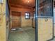Inside a well-maintained barn stall with a wooden door, hay on the floor, and metal bars at 23076 Oehlmann Park Rd, Conifer, CO 80433