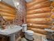 Charming powder room features log walls, floral wallpaper, vessel sink, and rustic accents at 23076 Oehlmann Park Rd, Conifer, CO 80433