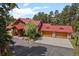 Beautiful log home with red roof and three-car garage nestled in lush greenery at 23076 Oehlmann Park Rd, Conifer, CO 80433