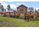 Log home with large windows and a spacious deck, backing onto a grassy lawn at 23076 Oehlmann Park Rd, Conifer, CO 80433