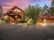 Front of a large log home with a porte-cochere, manicured landscaping, and a circular driveway at 23076 Oehlmann Park Rd, Conifer, CO 80433