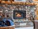 Close-up of a cozy stone fireplace with a wood mantel and burning logs, framed by rustic accents at 23076 Oehlmann Park Rd, Conifer, CO 80433