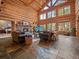 Spacious living room with stone fireplace, log walls, and large windows offering scenic views at 23076 Oehlmann Park Rd, Conifer, CO 80433