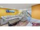 Basement living room features tile flooring, a large sectional sofa, and a bright yellow accent wall at 3242 Utica St, Denver, CO 80212