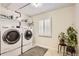 Well-lit laundry room featuring modern washer and dryer with shelf for storage and natural light at 2980 W Long Dr # E, Littleton, CO 80120