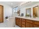 Bright bathroom featuring a double vanity, framed mirror, and bathtub with tiled surround at 13755 W Amherst Way, Lakewood, CO 80228