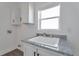 Bright laundry area with granite counters, cabinets, and sink under a window at 60600 E 56Th Ave, Strasburg, CO 80136