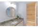 Bathroom vanity with granite countertop, decorative mirror, and adjacent tiled shower at 4877 Darwin Ct, Boulder, CO 80301