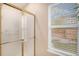 Bright bathroom featuring a shower with glass doors, and a sunlit window overlooking the fenced yard at 9705 Westbury Cir, Highlands Ranch, CO 80129