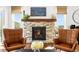 Living room fireplace with stone surround and hearth, flanked by leather chairs and large windows at 4706 Mesa Top Dr, Monument, CO 80132