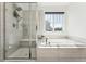 Bright bathroom featuring a shower with tile surround, a soaking tub, and a window at 2548 Horsehound Pl, Castle Rock, CO 80104