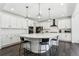 Open concept kitchen with white cabinets, black hardware and pendant lights over the large center island at 2548 Horsehound Pl, Castle Rock, CO 80104