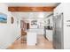Bright modern kitchen with white cabinetry, stainless steel appliances, island with seating, and a wood beam accent at 3521 W 40Th Ave, Denver, CO 80211