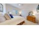 Comfortable bedroom with white walls, a bed with blue pillows, and wood dresser at 22674 E Henderson Dr, Aurora, CO 80016