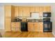 Well-lit kitchen showcasing light wood cabinets, sleek black appliances, and hardwood floors at 2434 S Williams St, Denver, CO 80210