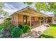 Brick home features a covered front porch, lush landscaping, and charming details at 1432 Xanthia St, Denver, CO 80220