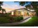 Charming brick home with a covered front porch and well-maintained landscaping at dusk at 1432 Xanthia St, Denver, CO 80220