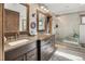Bathroom with double vanity, glass shower, and rustic wood trim at 1654 Muirfield Ln, Evergreen, CO 80439
