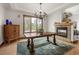 A formal dining room featuring wood floors, a fireplace and a rustic wood table under a decorative chandelier at 1654 Muirfield Ln, Evergreen, CO 80439