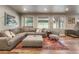 Basement living room features wood floors, natural light, a gray sectional, and a patterned rug at 1654 Muirfield Ln, Evergreen, CO 80439