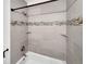 Modern bathroom featuring gray tiling, decorative tile accents, shower head and built-in shower shelves at 11422 W 17Th Pl, Lakewood, CO 80215