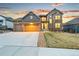 Inviting home exterior featuring a two-car garage, stone accents, well-manicured lawn, and neatly arranged rock garden at 18267 W 95Th Ave, Arvada, CO 80007
