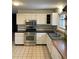 Traditional kitchen features white cabinets, tile backsplash, stainless steel appliances and neutral tile floors at 201 S Monmouth Ave, Firestone, CO 80520