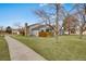 Well-maintained home exterior featuring a grassy lawn, brick chimney, and a cozy patio area at 14192 E Baltic Pl, Aurora, CO 80014