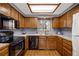 Functional kitchen with wood cabinets, black appliances, and ample counter space at 14192 E Baltic Pl, Aurora, CO 80014