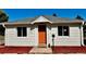 Charming home exterior featuring a bright orange front door and manicured landscaping at 601 W Layton Ave, Englewood, CO 80110