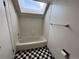 Clean bathroom with a bathtub, skylight, and checkerboard floor at 12484 W Nevada Pl # 210, Lakewood, CO 80228