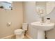 Clean half bathroom with a pedestal sink, modern fixtures, and round mirror at 16102 E 47Th Pl, Denver, CO 80239
