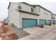 Exterior view of townhome garages, featuring turquoise doors and neutral siding at 16102 E 47Th Pl, Denver, CO 80239