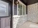 Inviting front porch with stone accents, sleek black door, and large window at 6532 N Malaya St, Aurora, CO 80019