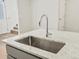 Close-up of a kitchen island featuring a stainless steel sink, faucet, and white countertop at 6532 N Malaya St, Aurora, CO 80019