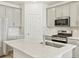 Bright kitchen features stainless steel appliances, white cabinets, and a large island with a sink at 6532 N Malaya St, Aurora, CO 80019