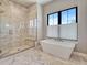 Bright bathroom features a soaking tub, glass enclosed shower and gray marble flooring at 2690 Fox View Trl, Franktown, CO 80116