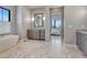 Elegant bathroom featuring a soaking tub, gray cabinets, marble floors, and a view to the bedroom at 2690 Fox View Trl, Franktown, CO 80116