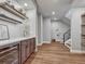 Hallway features a bar area, wood floors, and a view of staircase with floating shelves at 2690 Fox View Trl, Franktown, CO 80116