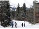 Winter ski scene of people walking in the snow near evergreen trees and a mountain in the background at 100 S Park Ave # E321, Breckenridge, CO 80424