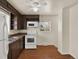 Traditional kitchen featuring dark cabinets, white appliances, and hardwood floors under a ceiling fan at 6800 Fern Dr, Denver, CO 80221