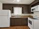 Well-lit kitchen featuring dark wooden cabinets, white appliances, and a double basin sink under a bright window at 6800 Fern Dr, Denver, CO 80221