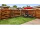 Cozy fenced backyard features artificial turf and patio furniture with a red umbrella at 1264 S Crystal Way, Aurora, CO 80012