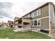 A view of the house from the back showing the covered patio with roll down shades and a nicely maintained lawn at 697 Sundance Cir, Erie, CO 80516