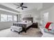 Spacious primary bedroom with a tray ceiling, ceiling fan, bench, and large windows at 697 Sundance Cir, Erie, CO 80516
