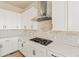 Modern kitchen features white cabinets, stainless steel hood, brick backsplash, and gas cooktop at 39417 Stockton Cir, Elizabeth, CO 80107